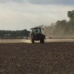 Tractor with spraying attachment working in field